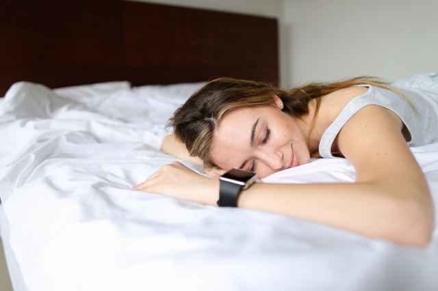 スマートウォッチを装着して寝る女性