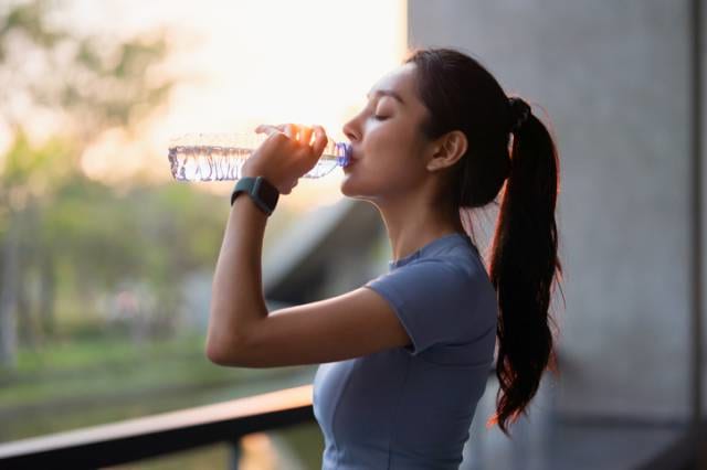 走って汗をかき水分補給する女性