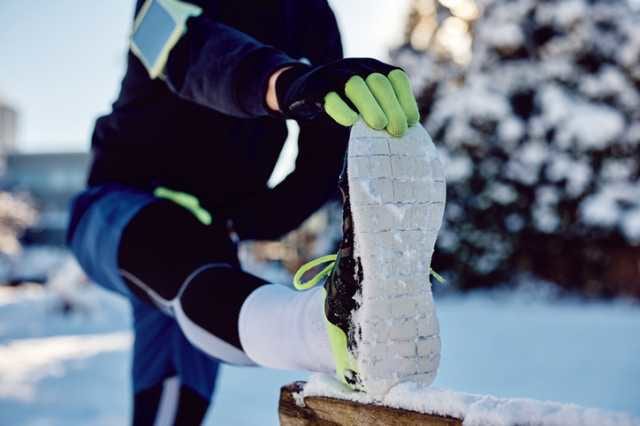 冬にスポーツタイツを履いて足をストレッチする男性