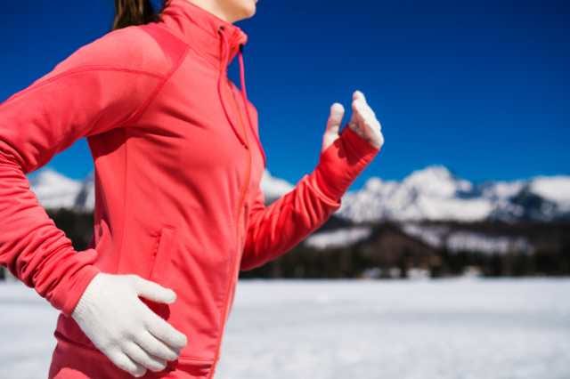 寒い冬に暖かい服装で走る女性ランナー