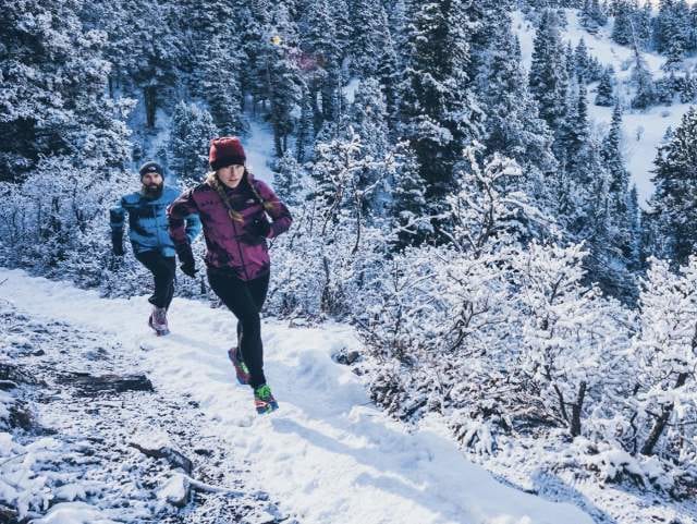 ザノースフェイスのウェアを着て雪山を走る男性と女性